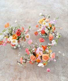 three vases filled with different types of flowers on the ground next to each other