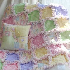 a crocheted blanket and two pillows on a bed in front of a window