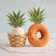 two pineapples and a doughnut on a doily with a cupcake