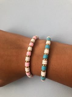 two bracelets with different colored beads on the arm, one is white and one is pink