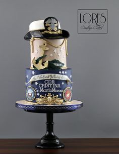 a three tiered cake decorated with hats and marine themed decorations on a wooden table