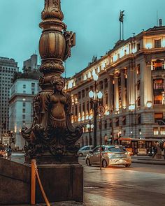 a lamp post in the middle of a city street at night with cars passing by