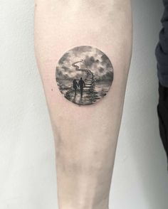 a man and woman standing on the beach under a full moon tattoo