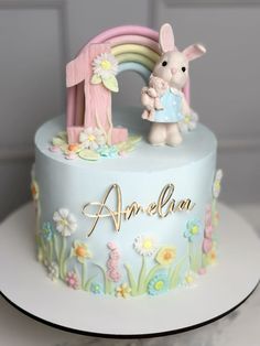 there is a small cake with a bunny and rainbow decoration on the top of it