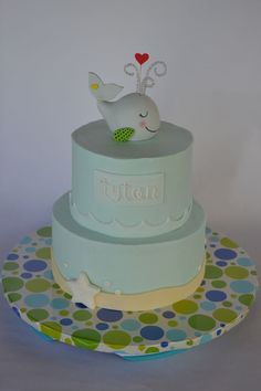 a three tiered cake with a whale on top and polka dot plates underneath it