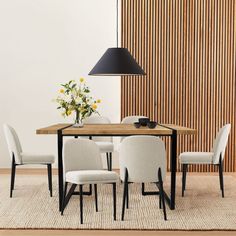 a dining room table with chairs and a lamp on top of it in front of a wooden paneled wall