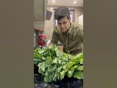 a man standing in front of a pile of green vegetables