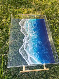 an acrylic painting on wood and glass with waves in the ocean behind it