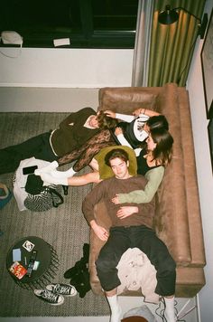 four people are laying on the floor in front of a couch with their arms around each other