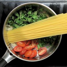 spaghetti and tomatoes are being cooked in a pot