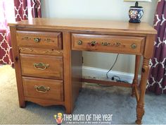 a wooden desk with two drawers and a lamp on it's end table in front of a curtained window