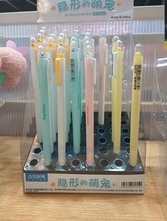 several different colored pens are in a display case on a table with a stuffed animal