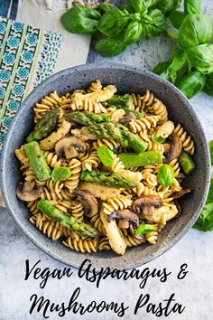 vegan asparagus and mushroom pasta in a bowl with basil on the side