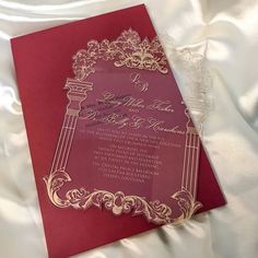 a red and gold wedding card on white satin