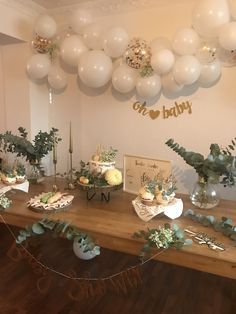 a table topped with lots of white balloons and greenery