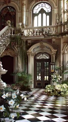 an ornate entry way with stairs and flowers on the floor in front of a checkerboard tile floor