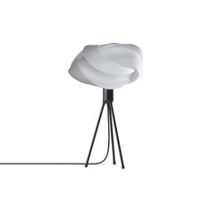 a white lamp sitting on top of a metal tripod light fixture with a black base