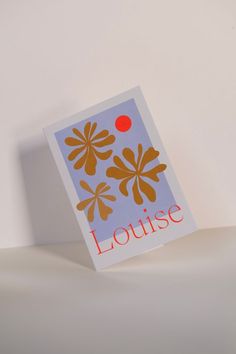 a card with an orange flower on it sitting on top of a white tablecloth