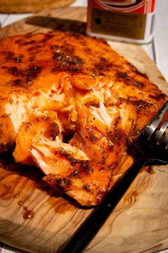 a wooden cutting board topped with meat on top of a table next to a knife