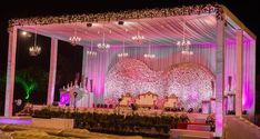 a decorated stage with couches and chandeliers in front of it at night