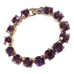 This vintage women's tennis bracelet showcases a 14+ carat purple amethyst gemstone, which has been lab-created and is perfectly round in shape. The gemstone is set in a gold tone metal with slight signs of wear, stone with minor loss,, but is still in overall good condition. Measuring 6.75 inches in length and 0.25 inches in height. Purple Jewelry With Jubilee Bracelet For Anniversary, Elegant Round Amethyst Crystal Bracelet, Elegant Purple Amethyst Tennis Bracelet, Purple Jubilee Tennis Bracelet, Classic Amethyst Bracelets In Purple, Classic Amethyst Purple Bracelets, Formal Amethyst Gemstone Tennis Bracelet, Classic Purple Tennis Bracelet As A Gift, Classic Purple Amethyst Bracelets