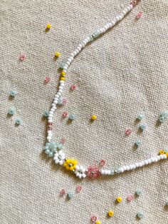 the beaded necklace is laying on top of the fabric with tiny beads all over it