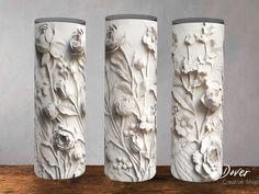 three white vases sitting on top of a wooden table