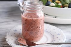 a jar filled with pink smoothie sitting on top of a white and blue plate