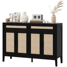 a black and beige sideboard with some vases on top of it next to a clock