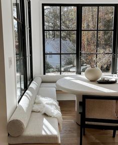 a white couch sitting in front of a window next to a table