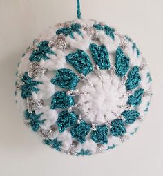 a crocheted ornament hanging from a hook on a wall in the shape of a snowflake