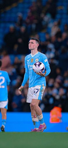 a man holding a soccer ball while standing on top of a field in front of a crowd