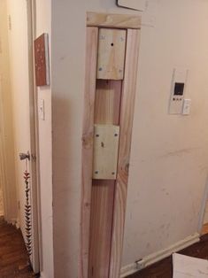 a wooden cabinet sitting on top of a hard wood floor next to a white wall