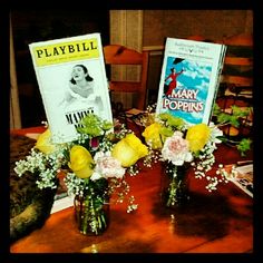 two vases filled with flowers sitting on top of a wooden table next to books