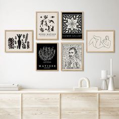 a living room with white walls and art on the wall, including framed pictures above a dresser