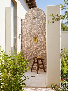 a walk in shower sitting next to a lush green bushy garden on the side of a house