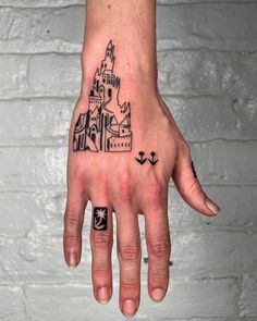 a person's hand with a castle tattoo on the left side of their palm