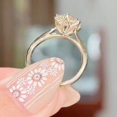 a close up of a person's hand holding a ring with flowers on it