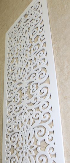 an intricately designed wall panel is shown on the floor in front of a beige background