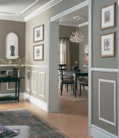 a living room filled with furniture and framed pictures on the wall next to a table