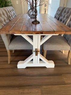 a wooden table sitting on top of a hard wood floor next to two gray chairs