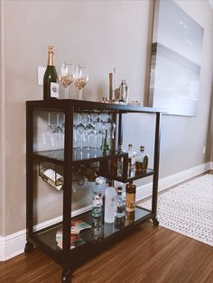 a bar cart with wine glasses and liquor bottles