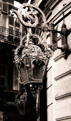 an old fashioned street light is attached to the side of a building with balconies