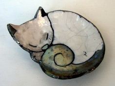 a ceramic cat sitting on top of a bowl