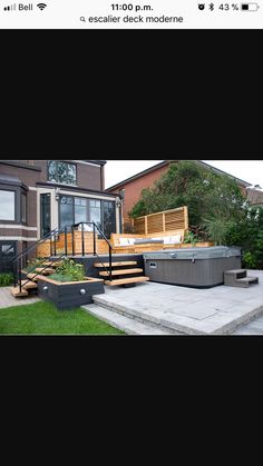 an outdoor hot tub sitting on top of a cement patio next to a house with stairs