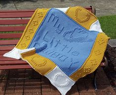 a crocheted blanket sitting on top of a wooden bench