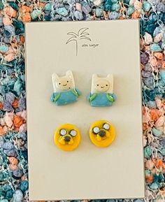 two yellow and blue cat earrings sitting on top of a card