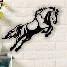 a horse running on its hind legs in front of a white brick wall with flowers