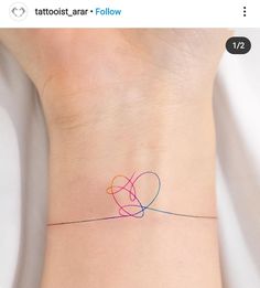 a small tattoo on the wrist of a woman's left arm that has an intertwined heart