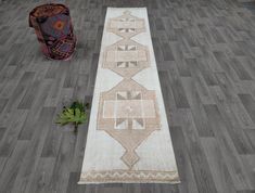 a white runner rug sitting on top of a wooden floor next to a potted plant